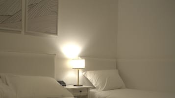 Una habitación de hotel con dos camas, una mesita de noche con lámpara y una obra de arte en la pared.