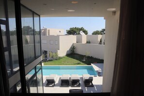 Un espace piscine moderne, doté de chaises longues et offrant une vue dégagée sur les bâtiments environnants.