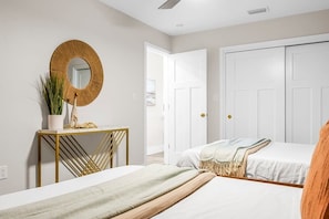 Une chambre à coucher avec un lit, des tables de chevet, un miroir et une armoire.