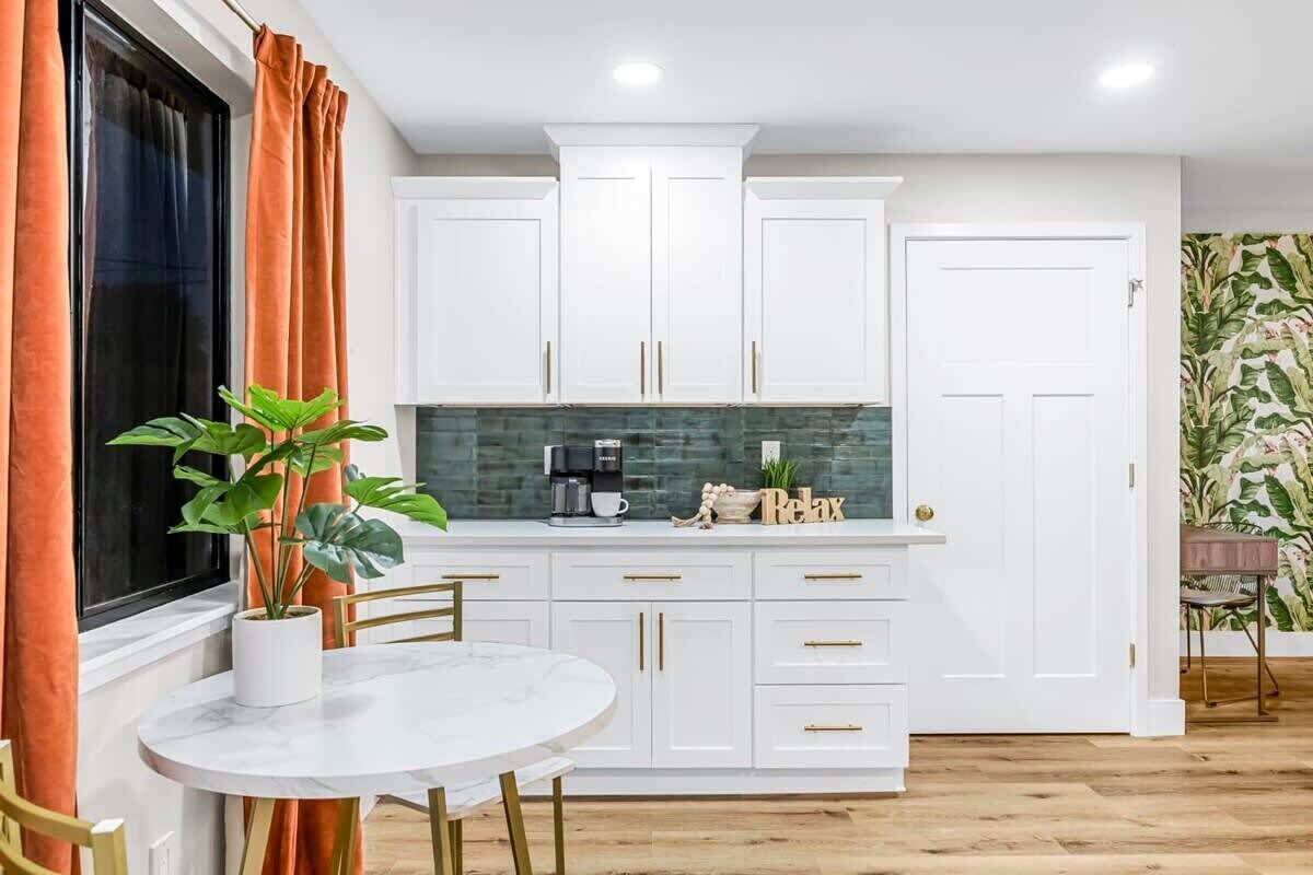 A kitchen with white cabinets, a marble table, and a potted plant.