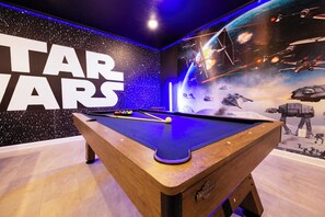 Una mesa de billar con decoración temática de Star Wars, incluyendo un mural grande y un cartel de Star Wars.