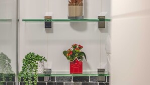 A bathroom with a glass shelf holding a potted plant, a decorative item, and a small vase. - Windsor Gem:3 Bed|2 Bath|Parking - By Tempstay (Windsor)