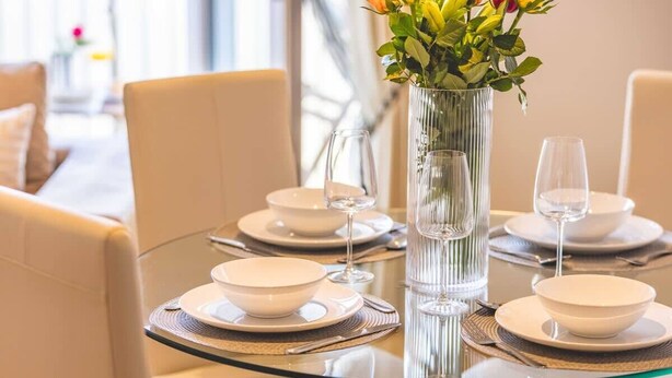 A dining table set with white plates, bowls, and wine glasses, with a vase of flowers in the center. - Windsor Gem:3 Bed|2 Bath|Parking - By Tempstay (Windsor)