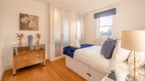 A bedroom with a bed, a dresser, a wardrobe, a window with a view, and a lamp. - Windsor Gem:3 Bed|2 Bath|Parking - By Tempstay (Windsor)