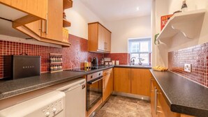 Una cocina compacta con armarios de madera, horno empotrado y ventana.