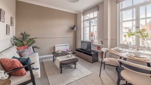 Una sala de estar moderna con sofá, mesa de centro, televisor y comedor.