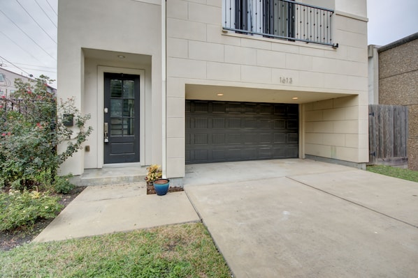 A modern two-story house with a garage, a front door, and a small balcony.