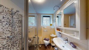 Enjoy a refreshing shower in the glass-enclosed shower, paired with a spacious vanity and large mirror.