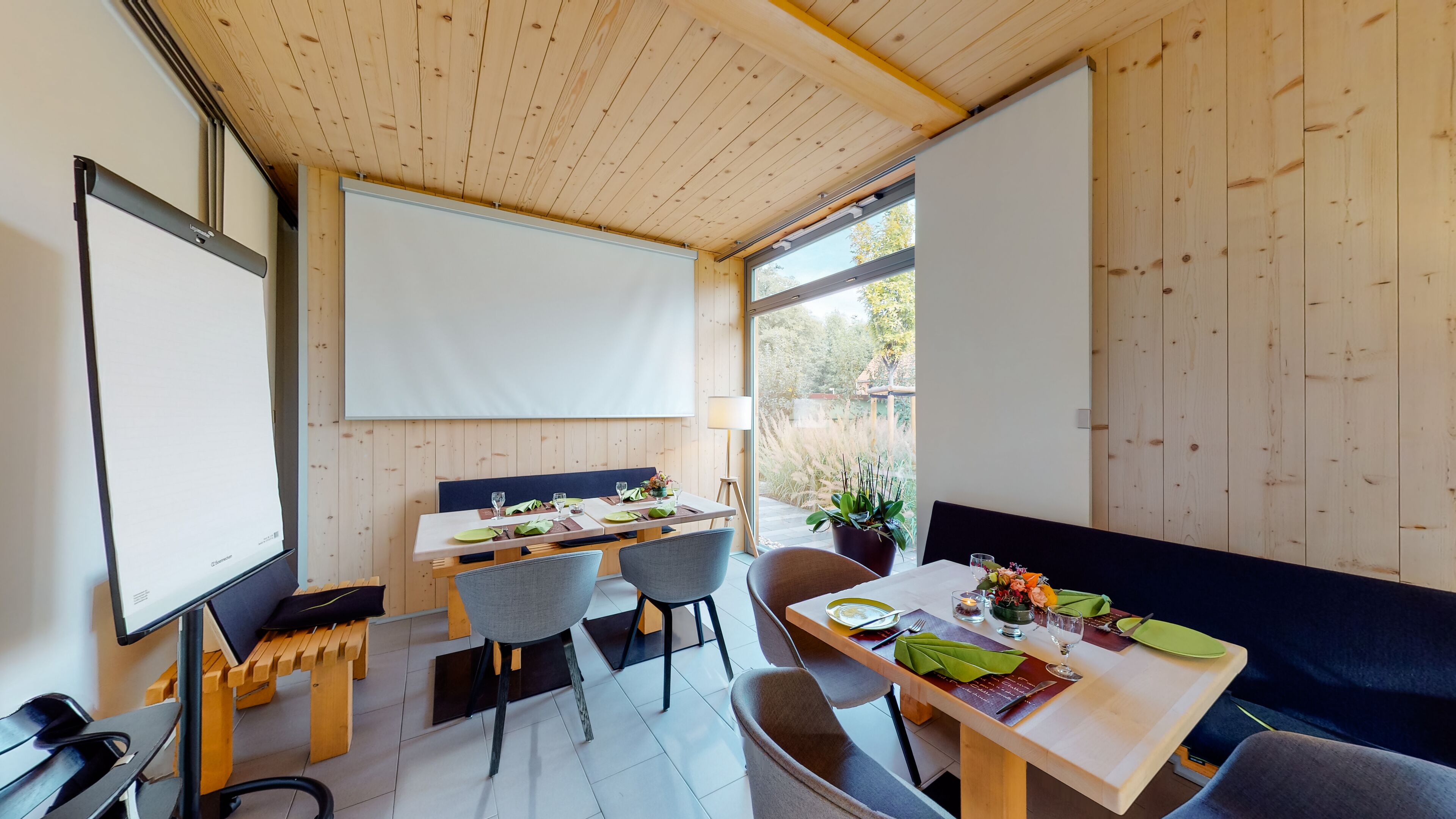 Un espace repas moderne avec des murs et un plafond en bois, une grande fenêtre et un tableau blanc.