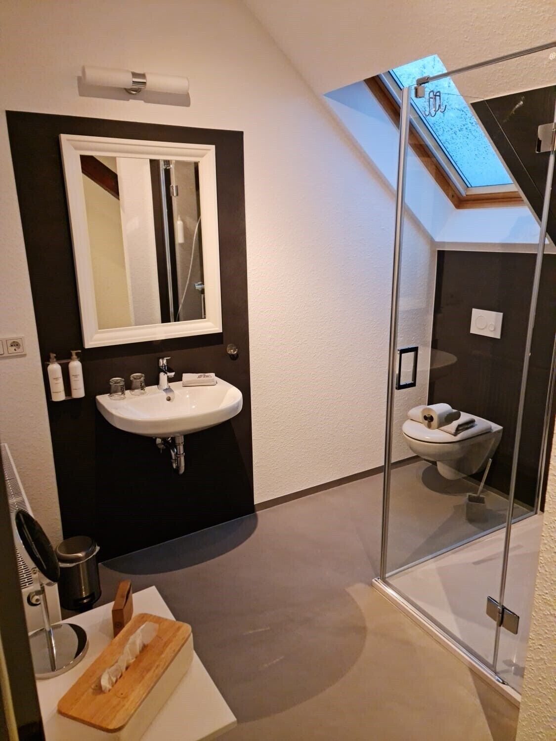 Un baño moderno con cabina de ducha de vidrio, un lavabo blanco y un espejo sobre él.