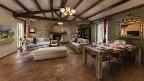 A spacious living room with a fireplace, stone walls, and a dining area with wooden furniture. - Le Chateau (Visnjan)