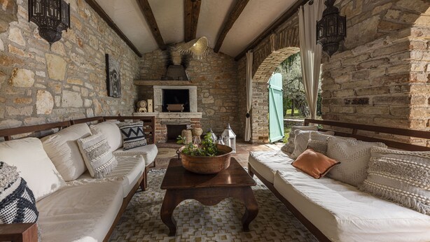 A cozy room with stone walls, a fireplace, and a large window. - Le Chateau (Visnjan)