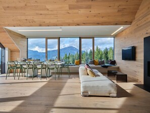 Un intérieur moderne comprenant un coin repas, des sièges et une grande fenêtre offrant une vue sur les montagnes.