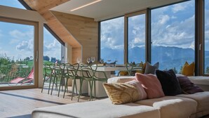 Un salon moderne doté d’une grande fenêtre, d’un canapé et d’un coin repas avec des chaises et une table.