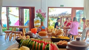 A buffet table with various fruits, pastries, and a large watermelon centerpiece. - Pousada Varanda Amar (Amontada)