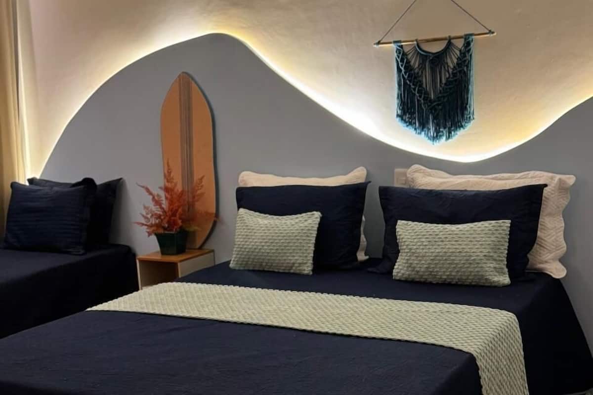 Une chambre moderne avec deux lits, un grand miroir et une décoration murale en macramé.