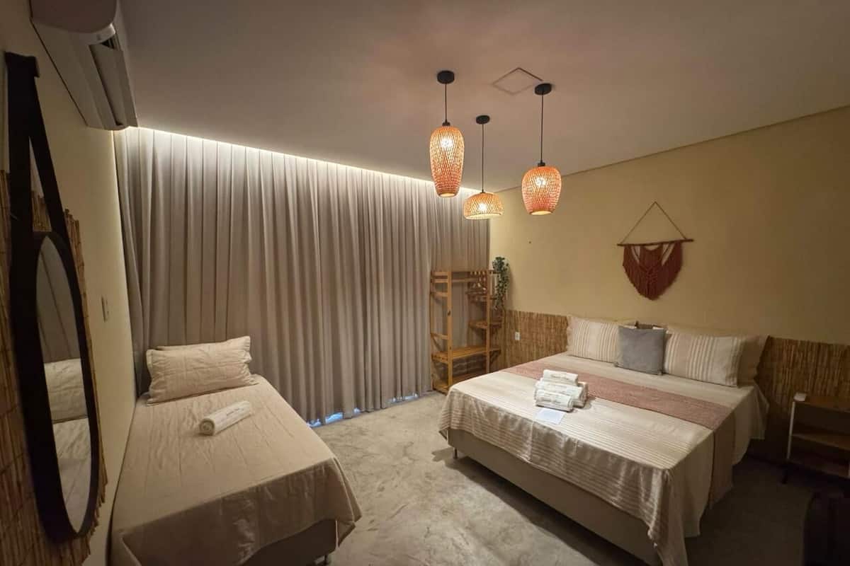 Une chambre d’hôtel avec deux lits, un grand miroir, une armoire et une plante suspendue.