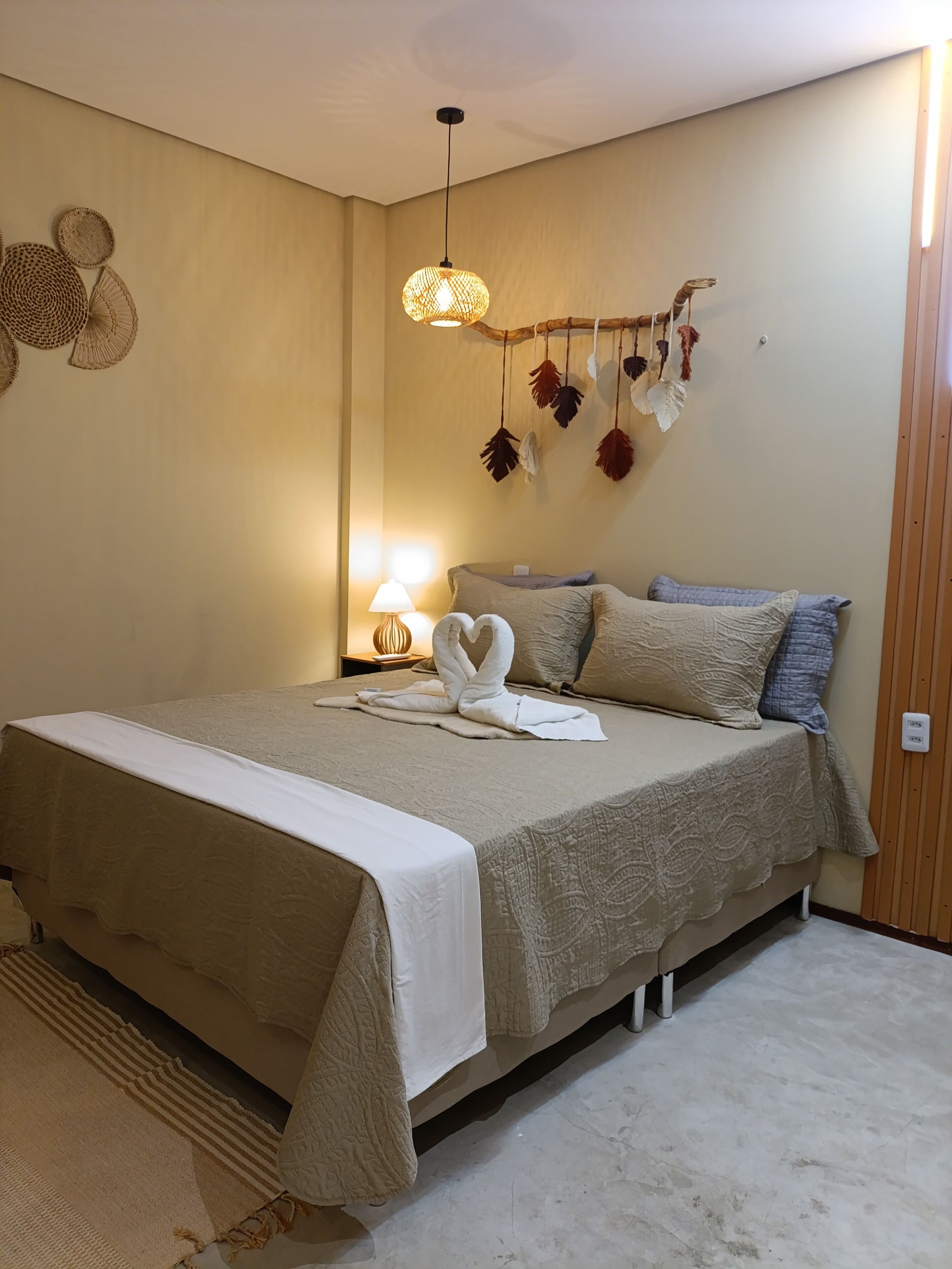 A neatly arranged bedroom with a bed, pillows, a bedside lamp, and wall decorations.