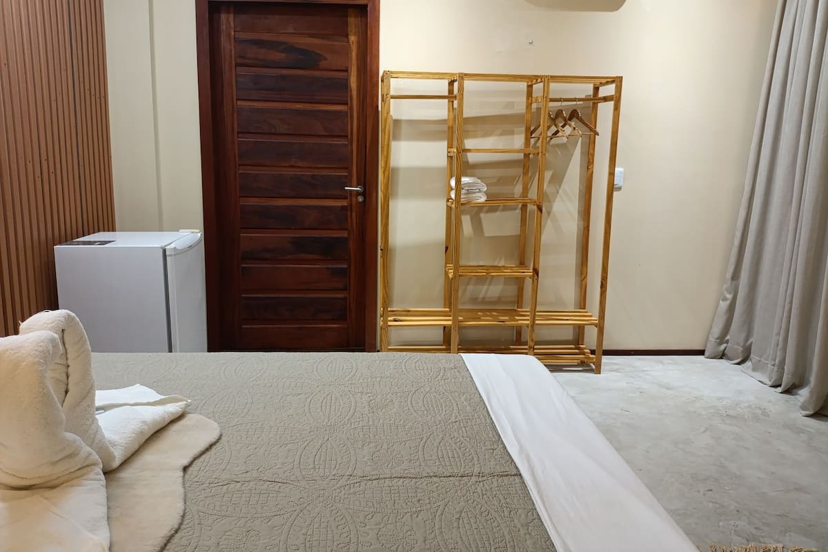 Une chambre à coucher comprenant un lit, une armoire, un petit appareil électroménager blanc et une porte en bois.
