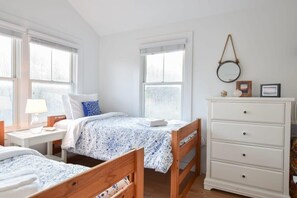 A bedroom with two single beds, a white dresser, and a small table with a lamp. - Just a few steps to Ellis Landing Beach! (Brewster)