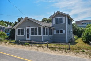 A two-story house with a gabled roof, a front porch, and a fenced yard. - Just a few steps to Ellis Landing Beach! (Brewster)