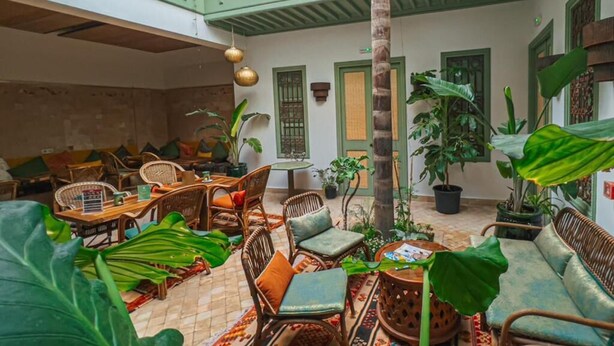 Un vaste espace intérieur doté de hauts plafonds, de meubles en osier et de plantes en pot.