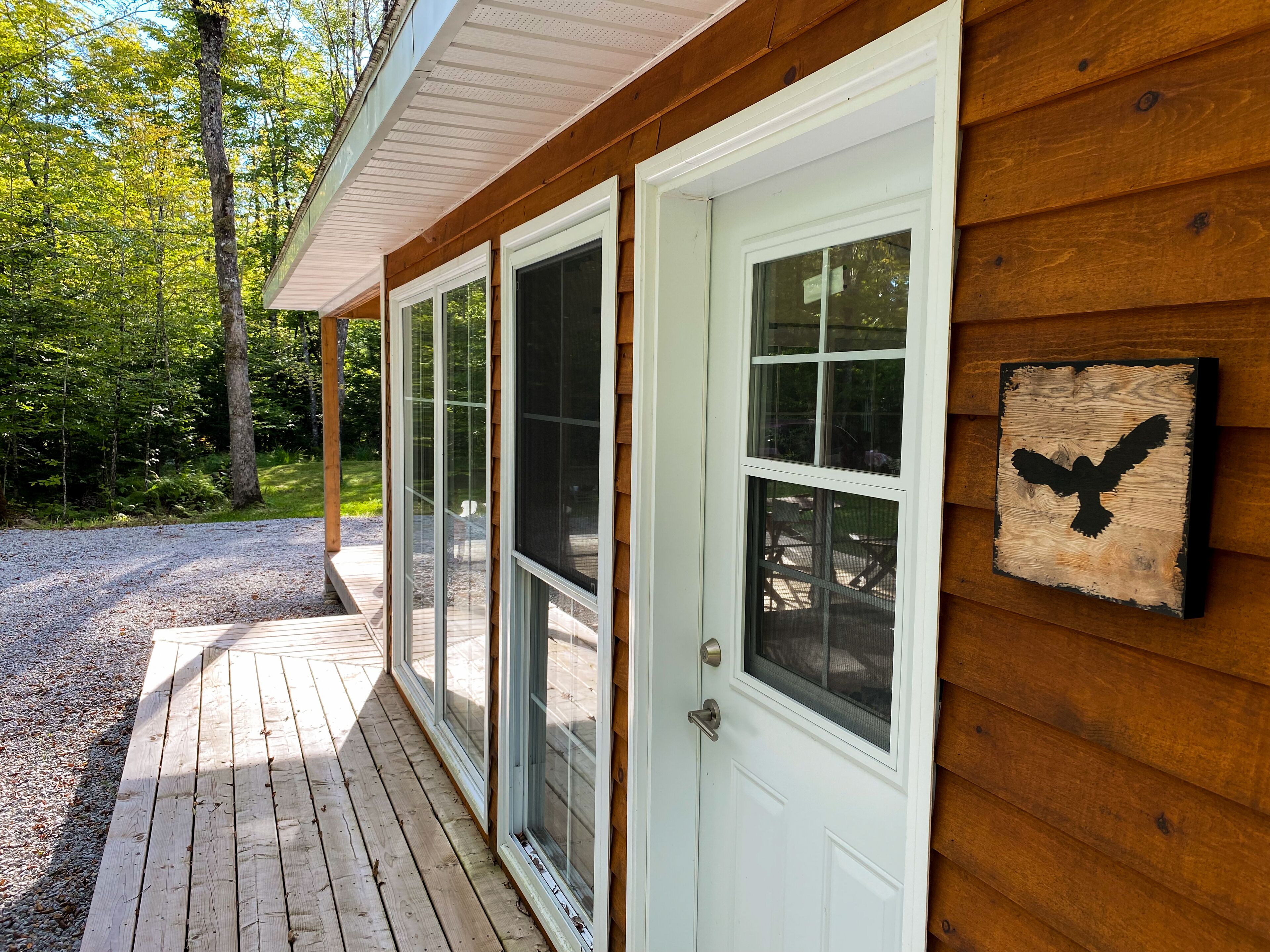 A wooden building with a porch, large windows, and a bird silhouette decoration.