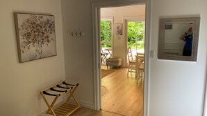 A hallway leading to a dining area with a wooden bench, a framed artwork, and a mirror on the wall.