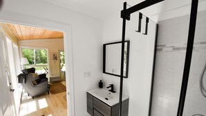 A modern bathroom with a white vanity, a black towel rack, and a shower with a glass door.