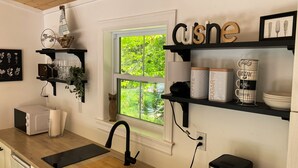 A kitchen with black shelves, a window, and a microwave.