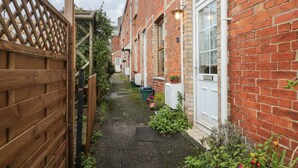 A narrow alleyway between terraced houses with brick walls, a wooden gate, and a pathway. - Oakman Cottage (Honiton)