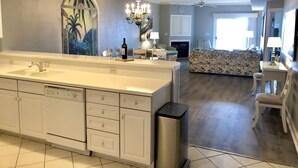 A spacious kitchen with a large island, a dining area with a floral sofa, and a view of the living room.