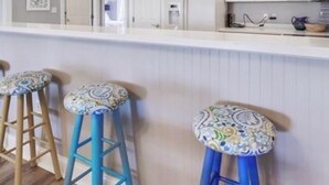 A kitchen with white cabinets, a countertop, and three stools with patterned seat covers.