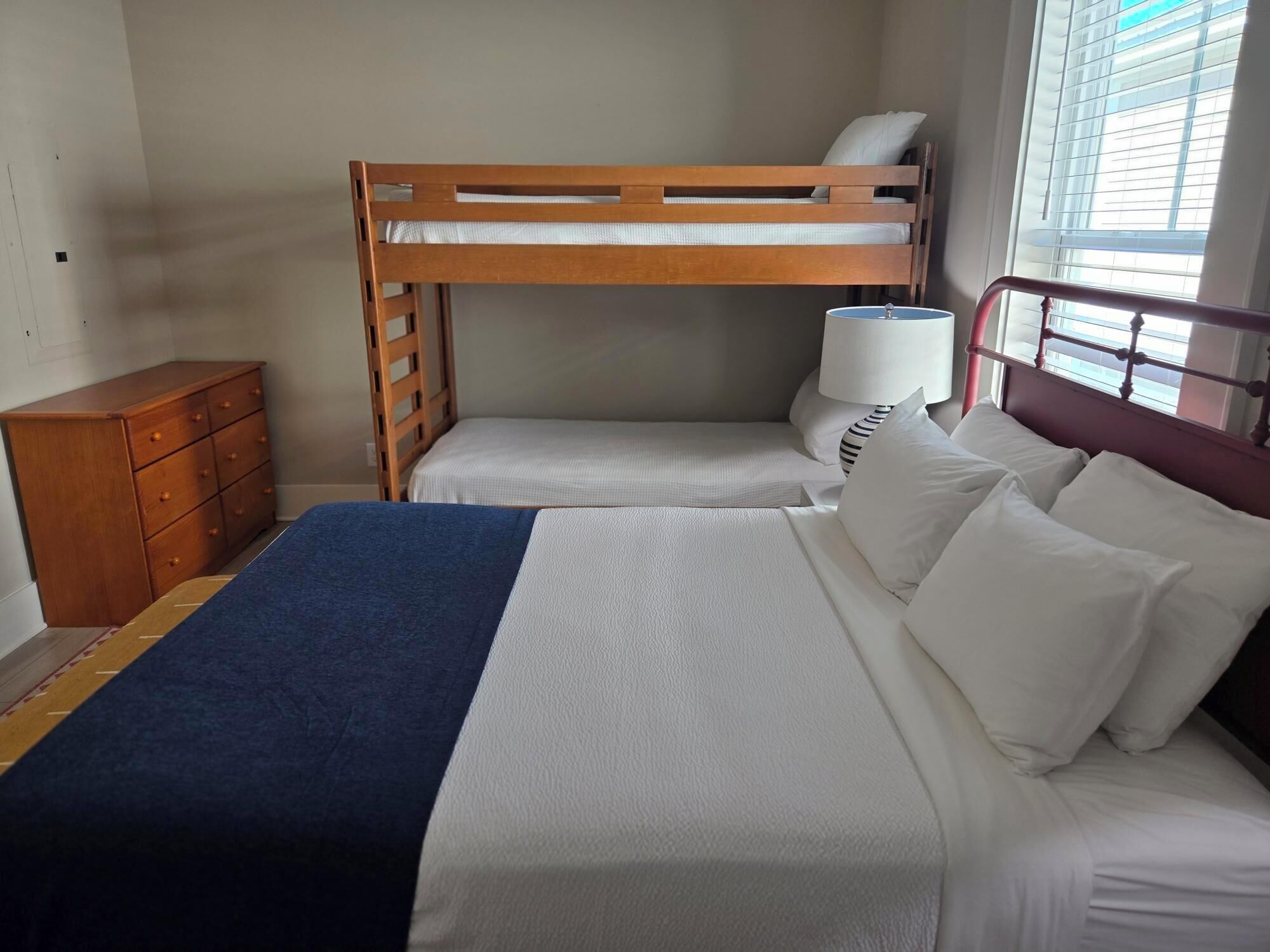 Un letto a castello con struttura in legno, un comodino con una lampada e un armadio.