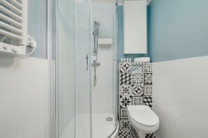 A bathroom with a shower, toilet, and a towel rack. - Bright Apartment with Bedroom | Good Location in Katowice. (Katowice)