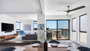 A modern living room with a dining area, large windows, and a view of the sea. - Ocean View | Steps to DT Manhattan Beach|King Beds (Manhattan Beach)
