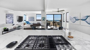 A modern kitchen with a large island, a dining area with a view, and a living room with a sofa and chairs. - Ocean View | Steps to DT Manhattan Beach|King Beds (Manhattan Beach)