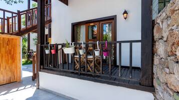 Un balcon en bois agrémenté de plantes en pot et d’une table avec des chaises.