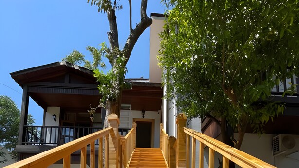Un escalier en bois menant à un bâtiment doté d’un balcon.