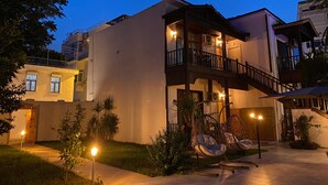Un immeuble à plusieurs étages doté de balcons, d’un espace extérieur aménagé pour s’asseoir et d’une entrée bien éclairée.