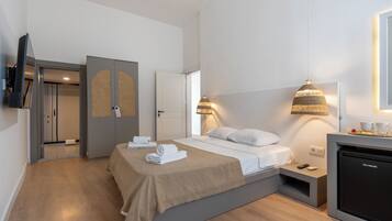 Una habitación de hotel moderna con cama, mesitas de noche, televisor y minibar.