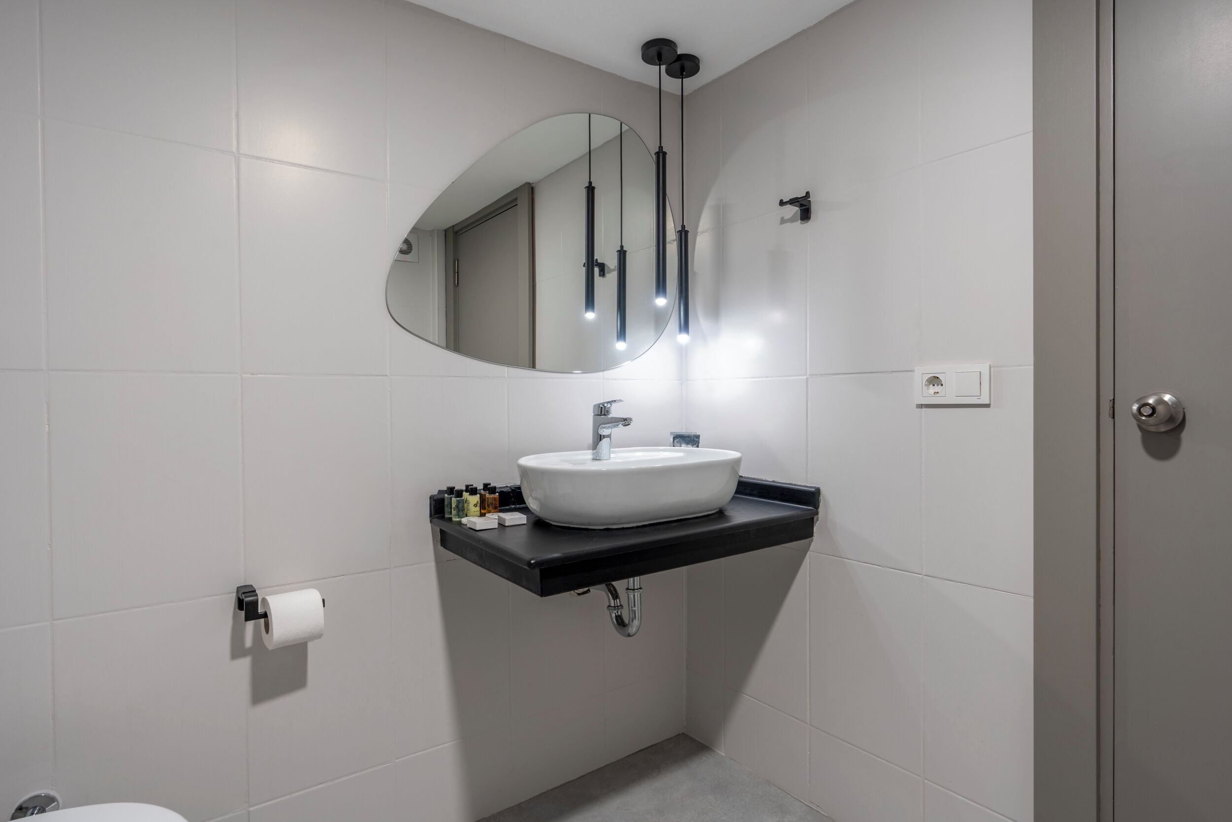 Een moderne badkamer met een wit wastafelmeubel, een zwart aanrechtblad en een grote spiegel.