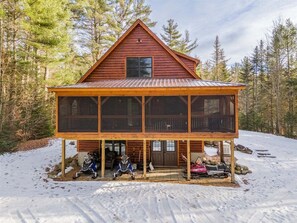 A cabin with a large deck, a covered porch, and a snow-covered ground. - Deer Run - Chalet w/ Fireplace (Greenwood)