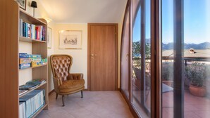 A room with a large window, a bookshelf, a leather chair, and a door. - Apartment Bella Sathea (Torri del Benaco)