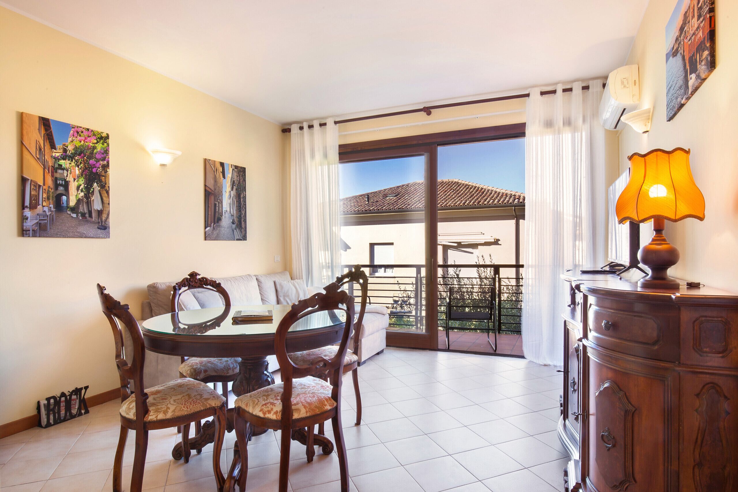 Un área de comedor con una mesa redonda y sillas, un sofá, una lámpara y obras de arte en las paredes.