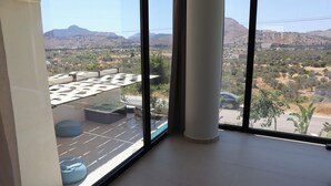 Ein Zimmer mit großen Fenstern, gefliestem Boden und Blick auf eine Berglandschaft.