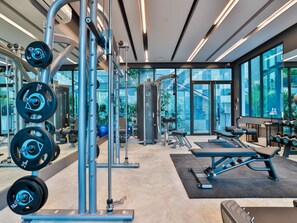 A modern gym with weightlifting equipment, exercise machines, and large windows offering views of the outdoors. - BO202- 1 Bedroom Serviced Apartment With Sea View at Ao Nang Beach (Tambon Ao Nang)