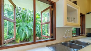 A kitchen with large windows, a sink, and a cabinet with glass jars.