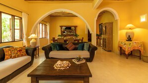 A cozy living room with a sofa, coffee table, and a dining area with a table and chairs.