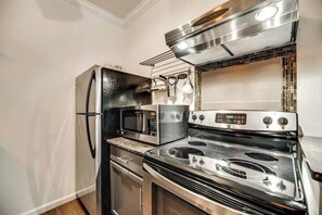 Una cucina con elettrodomestici in acciaio inossidabile, tra cui frigorifero, microonde, forno e piano cottura.